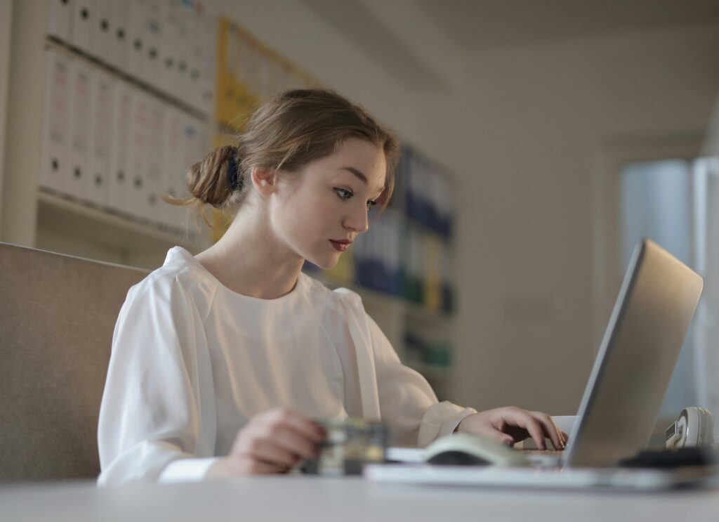pexels-photo-3784337-3784337 Focused woman in white working on a laptop in a modern office setting.